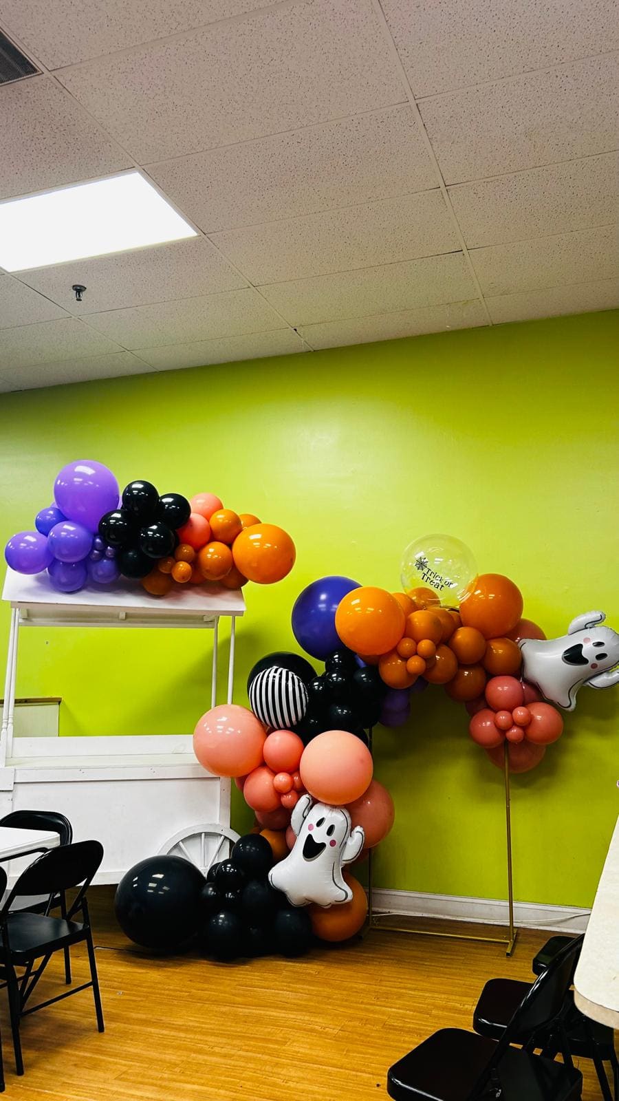 Candy cart with an orange, black and purple Halloween balloon garland and backdrop