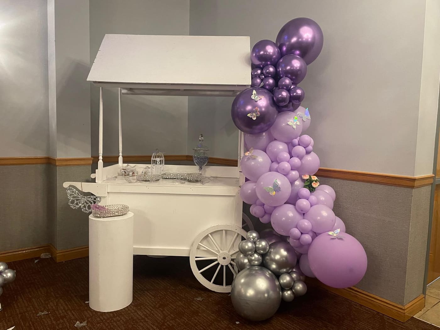 White candy cart styled with a purple and silver balloon garland