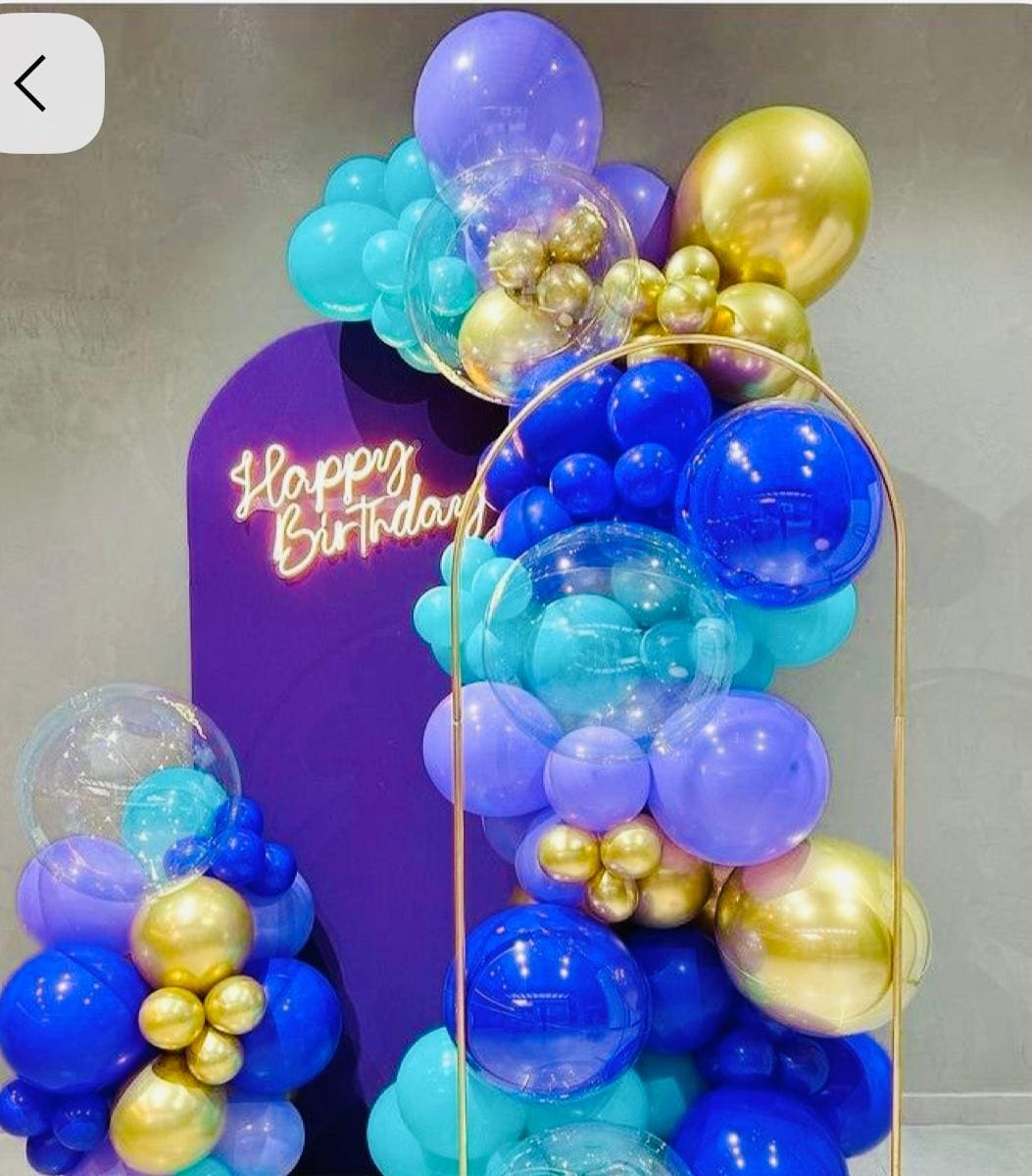 Blue, purple and gold balloon garland backdrop with a Happy Birthday neon sign